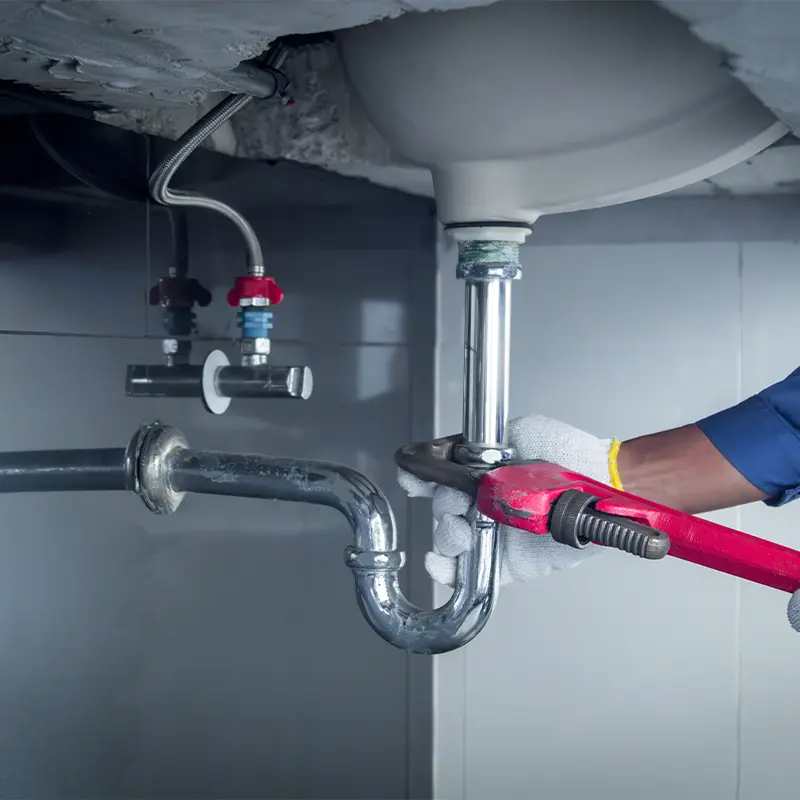 Plombier en Essonne raccordant la tuyauterie sous lavabo lors d'une rénovation de salle de bain dans le 91